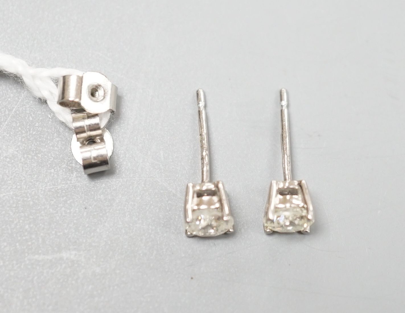 A modern pair of platinum and solitaire diamond set ear studs, total carat weight approx. 0.86ct.